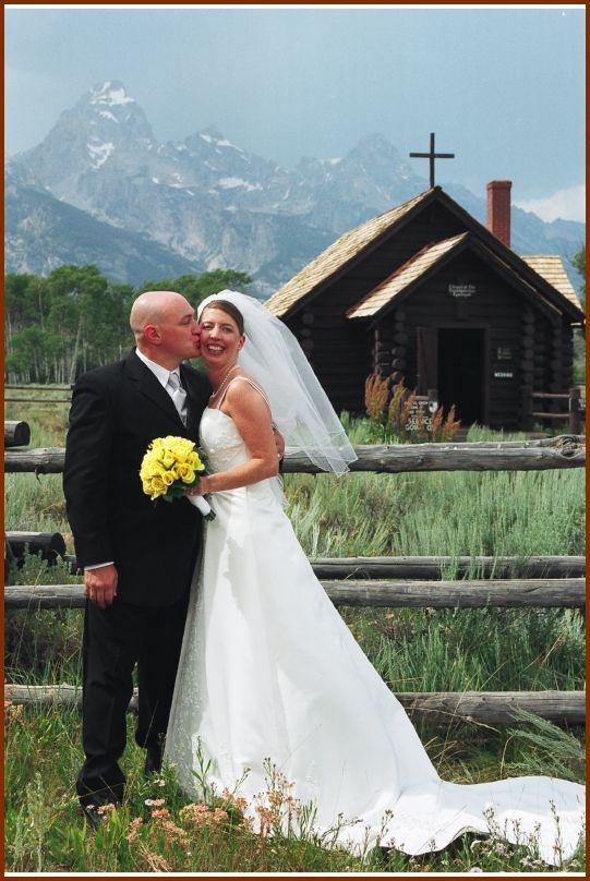 Kiss in front of Chapel & Tetons
